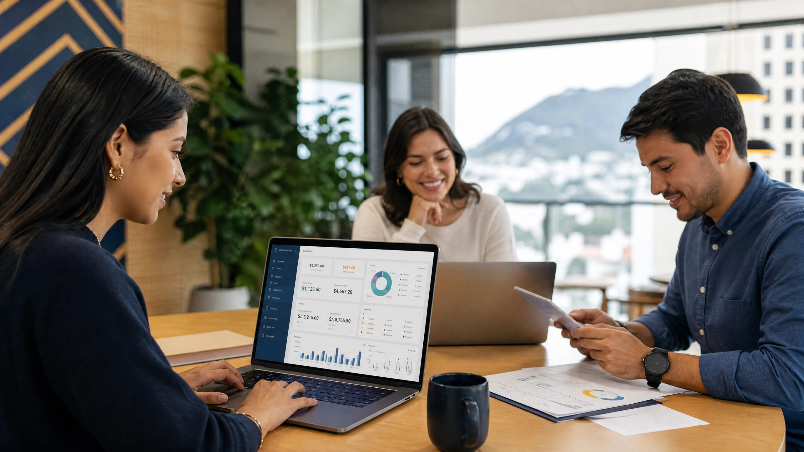 Tres colegas reunidos alrededor de una mesa de oficina revisando un panel financiero en una laptop